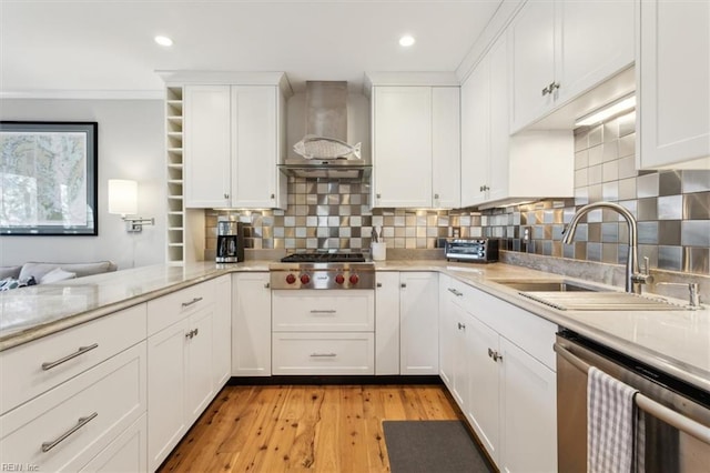 kitchen with appliances with stainless steel finishes, white cabinets, sink, and wall chimney exhaust hood