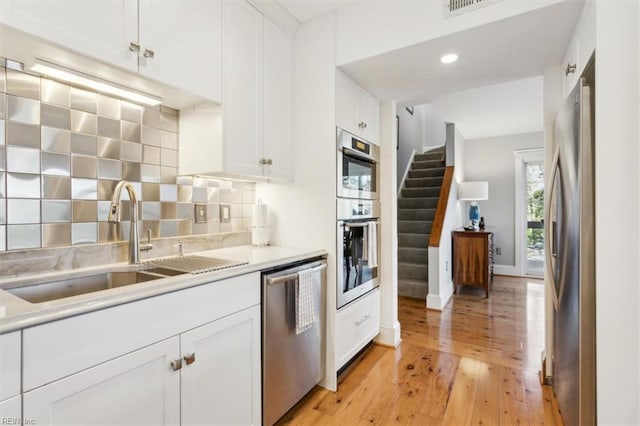 kitchen with appliances with stainless steel finishes, white cabinets, backsplash, and sink