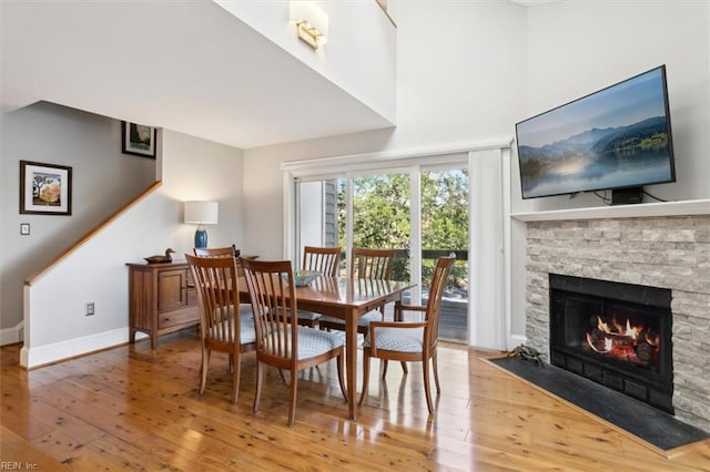 dining area with hardwood / wood-style flooring and a stone fireplace