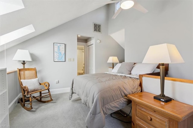 bedroom with lofted ceiling with skylight, ensuite bathroom, ceiling fan, and light colored carpet