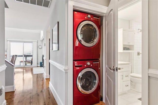 clothes washing area featuring stacked washer and clothes dryer and light hardwood / wood-style flooring