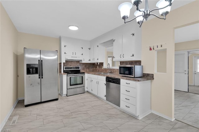 kitchen with stainless steel appliances, sink, white cabinetry, tasteful backsplash, and a chandelier