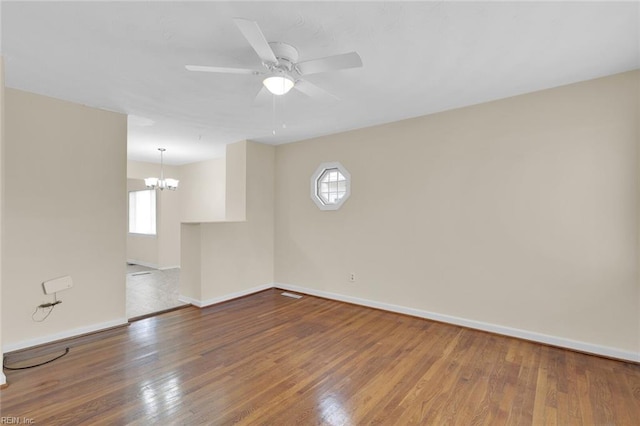 spare room with ceiling fan with notable chandelier and hardwood / wood-style floors