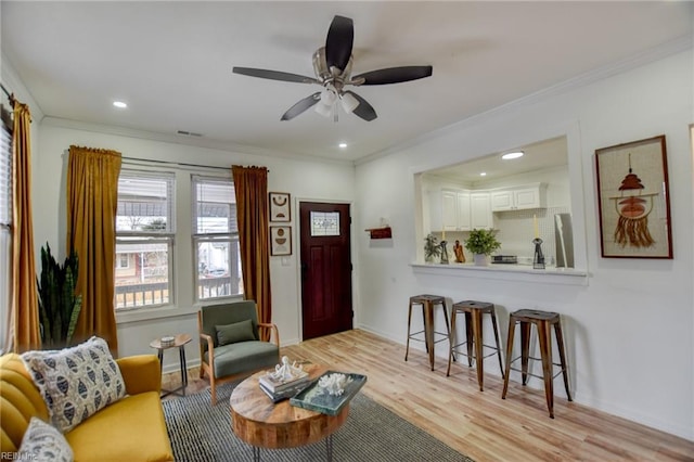 living room with light hardwood / wood-style floors, crown molding, and ceiling fan