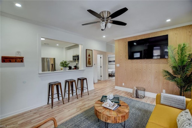 living room featuring wooden walls, ornamental molding, and light hardwood / wood-style floors