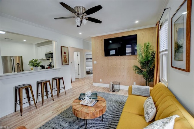 living room with ceiling fan, light wood-type flooring, and crown molding