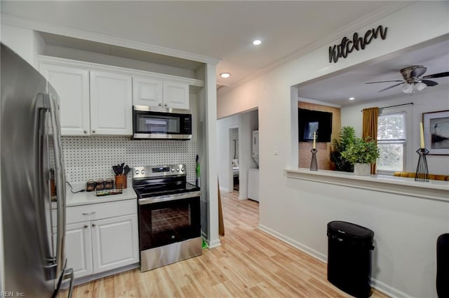 kitchen with backsplash, light hardwood / wood-style floors, crown molding, appliances with stainless steel finishes, and white cabinets