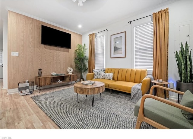 living room featuring ceiling fan, wood walls, ornamental molding, and hardwood / wood-style flooring