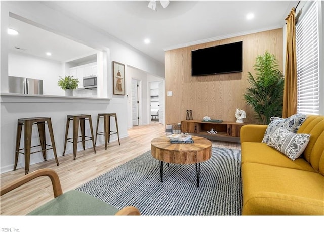 living room with light wood-type flooring and wood walls