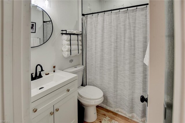 bathroom featuring toilet, vanity, a shower with shower curtain, and hardwood / wood-style floors