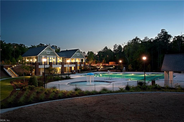 pool at dusk with pool water feature and a patio