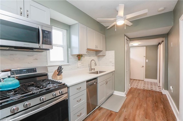 kitchen with stainless steel appliances, sink, white cabinets, light hardwood / wood-style flooring, and decorative backsplash