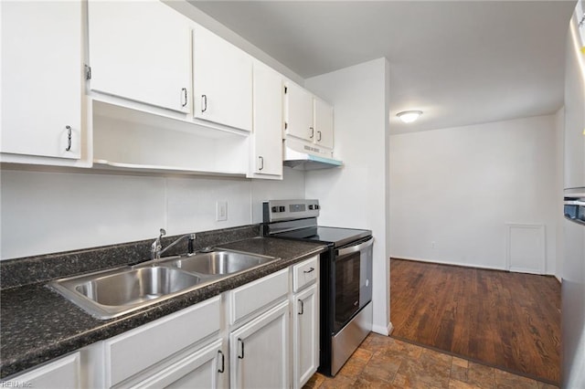 kitchen featuring sink, stainless steel range with electric cooktop, dark stone countertops, and white cabinetry