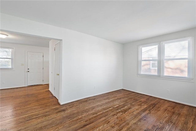 spare room featuring plenty of natural light and dark hardwood / wood-style floors