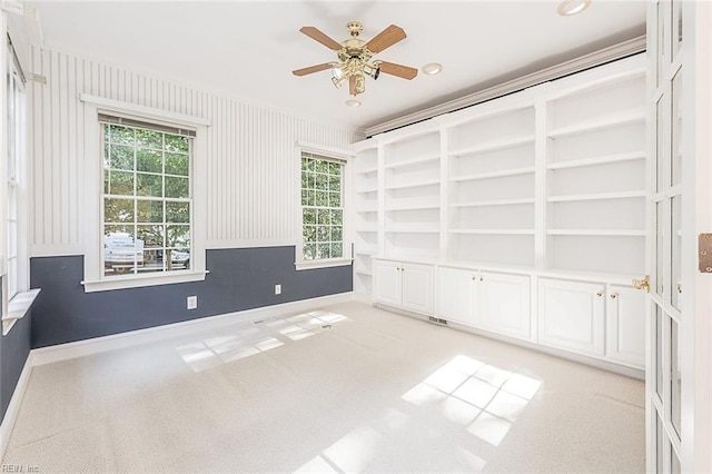 spare room with ceiling fan, light colored carpet, and crown molding