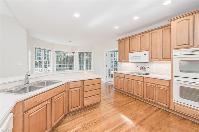 kitchen with white appliances, light hardwood / wood-style floors, pendant lighting, and sink