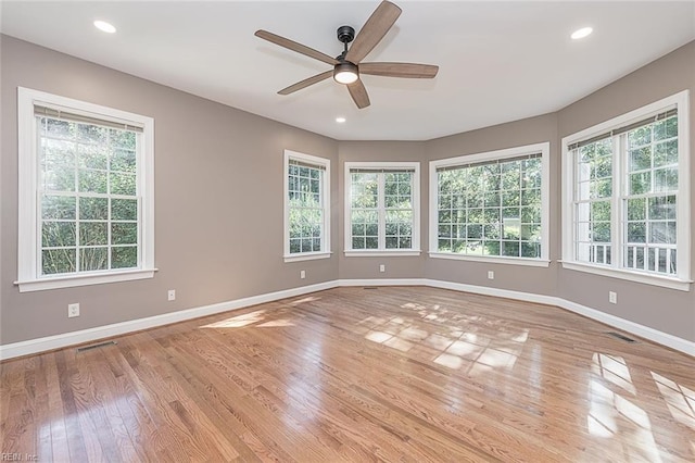 spare room with ceiling fan, a healthy amount of sunlight, and light wood-type flooring