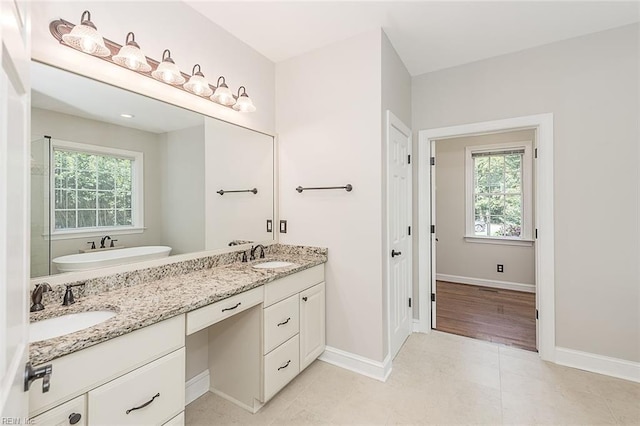 bathroom with a washtub, tile patterned floors, a wealth of natural light, and vanity