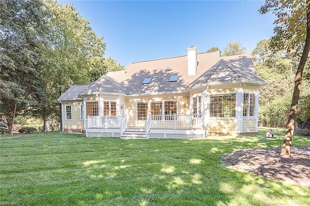 back of property with a wooden deck and a lawn