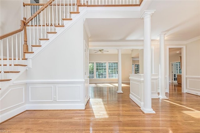 stairway with ornate columns, wood-type flooring, ceiling fan, and crown molding