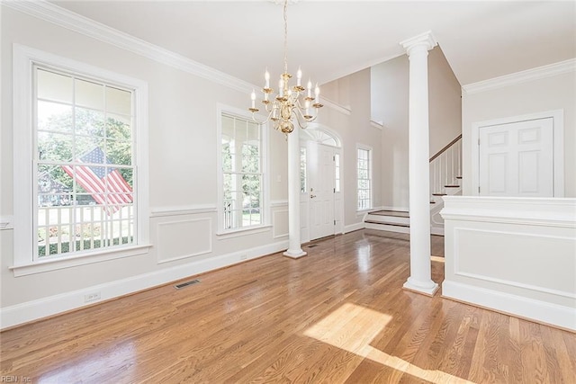 interior space with decorative columns, wood-type flooring, ornamental molding, and a chandelier