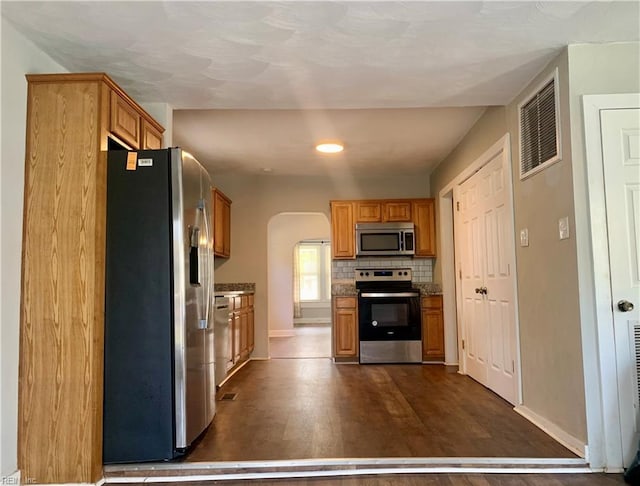 kitchen featuring dark hardwood / wood-style floors, backsplash, and appliances with stainless steel finishes