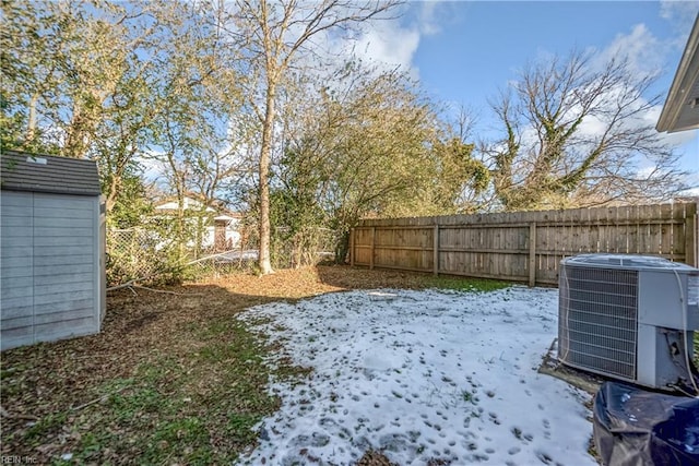 yard covered in snow featuring central AC and a shed