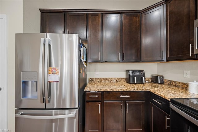 kitchen with stainless steel fridge, light stone counters, and dark brown cabinetry