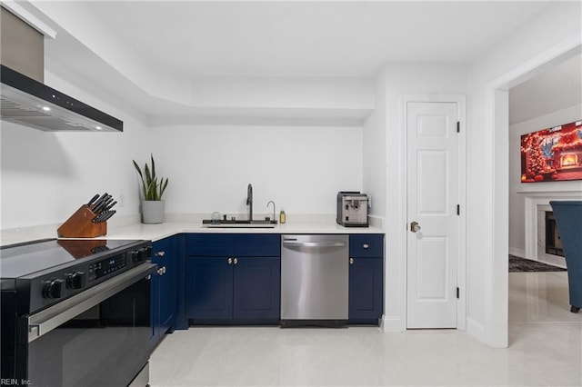 kitchen featuring appliances with stainless steel finishes, wall chimney exhaust hood, sink, blue cabinets, and light tile patterned flooring