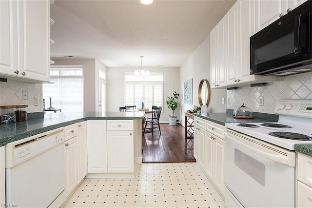 kitchen featuring white appliances, a chandelier, kitchen peninsula, pendant lighting, and white cabinets