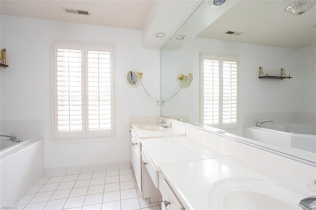 bathroom with tile patterned floors, tiled tub, and vanity