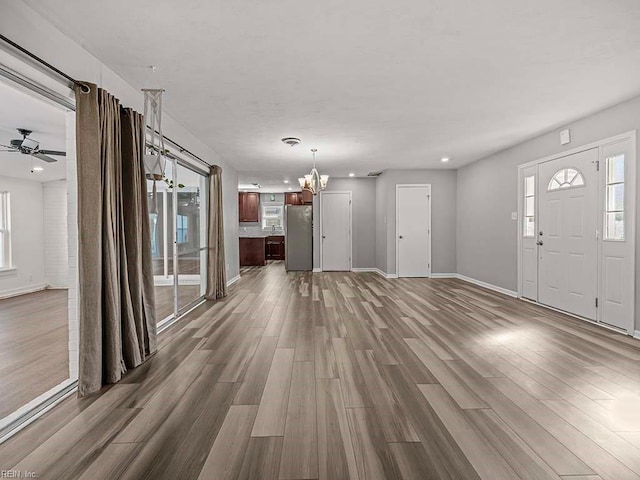 unfurnished living room with hardwood / wood-style floors and ceiling fan with notable chandelier