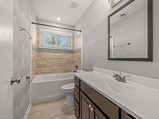 full bathroom with tile patterned flooring, tiled shower / bath combo, vanity, and toilet