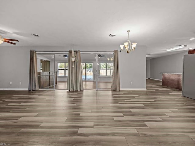 empty room with hardwood / wood-style flooring and ceiling fan with notable chandelier