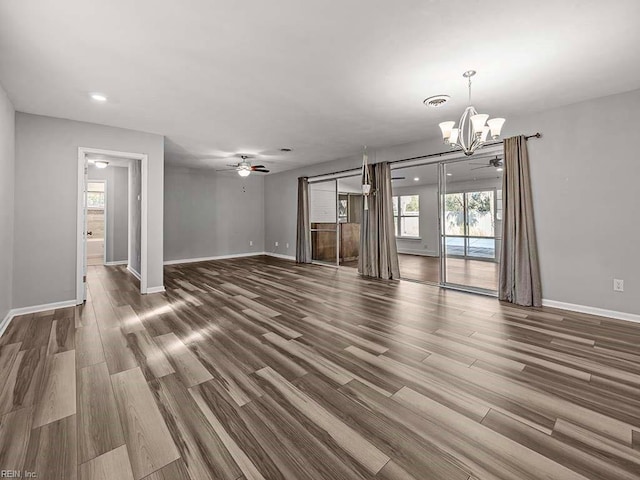 unfurnished living room with ceiling fan with notable chandelier and hardwood / wood-style flooring