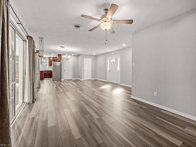 unfurnished living room featuring dark wood-type flooring and ceiling fan with notable chandelier