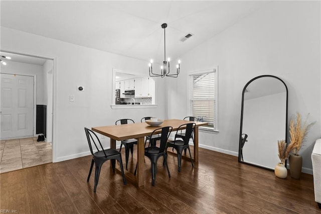 dining space with vaulted ceiling, dark hardwood / wood-style floors, and a notable chandelier