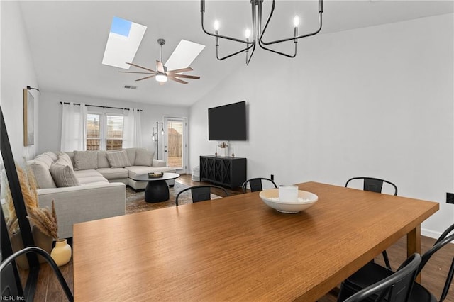 dining area with high vaulted ceiling, a skylight, ceiling fan with notable chandelier, and hardwood / wood-style flooring