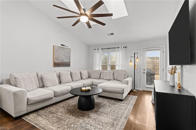 living room with ceiling fan, a skylight, dark hardwood / wood-style flooring, and high vaulted ceiling