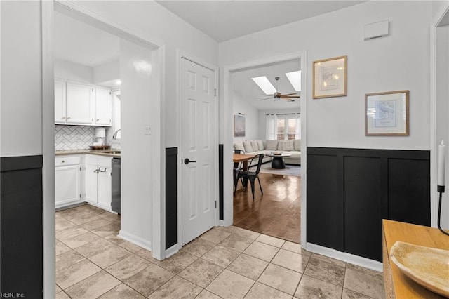 interior space with ceiling fan, dishwasher, decorative backsplash, light tile patterned floors, and white cabinets