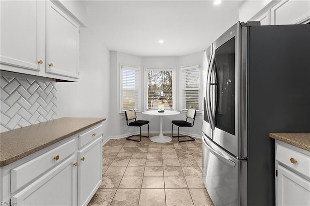 kitchen with decorative backsplash, light tile patterned floors, white cabinetry, and stainless steel fridge