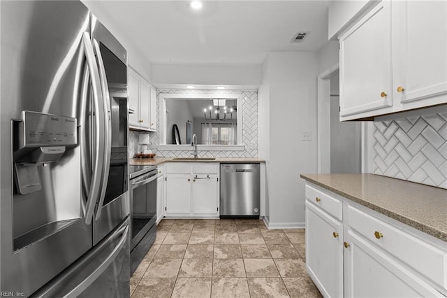 kitchen with stainless steel appliances, decorative backsplash, white cabinetry, and sink