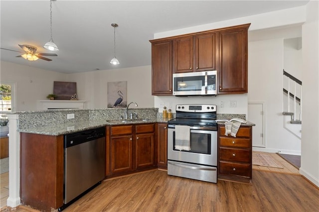 kitchen featuring stainless steel appliances, light wood-type flooring, light stone countertops, ceiling fan, and sink