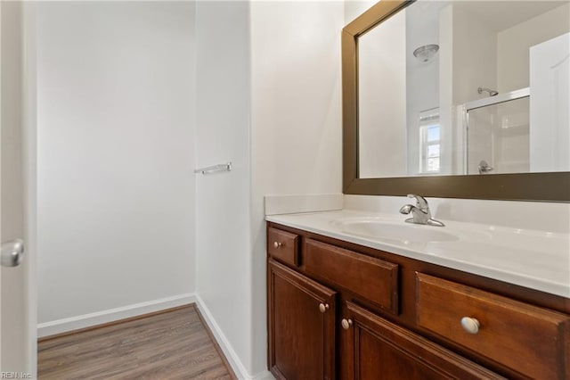 bathroom with hardwood / wood-style floors, a shower with door, and vanity