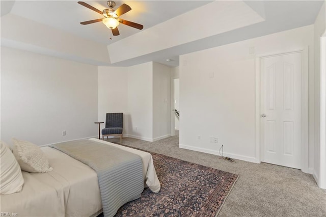 carpeted bedroom featuring ceiling fan and a tray ceiling