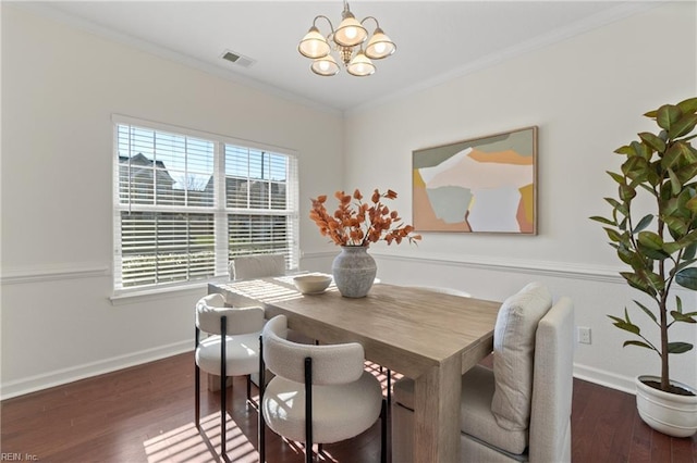 dining area featuring ornamental molding, dark wood-type flooring, and a notable chandelier