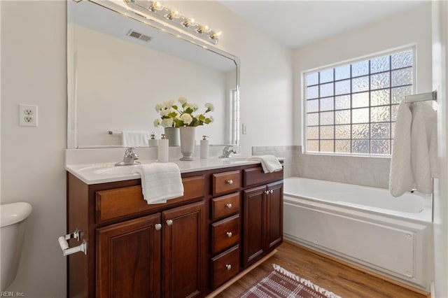 bathroom with wood-type flooring, toilet, vanity, and a bathing tub