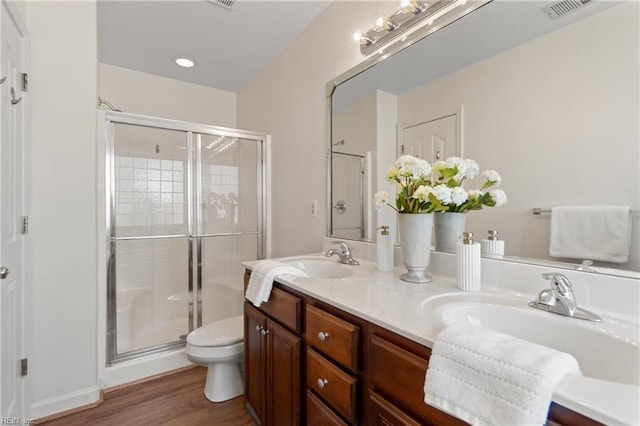 bathroom featuring toilet, hardwood / wood-style flooring, walk in shower, and vanity