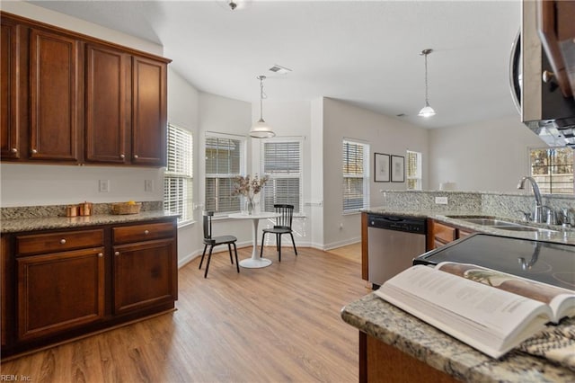 kitchen with sink, decorative light fixtures, dark stone countertops, light hardwood / wood-style flooring, and appliances with stainless steel finishes