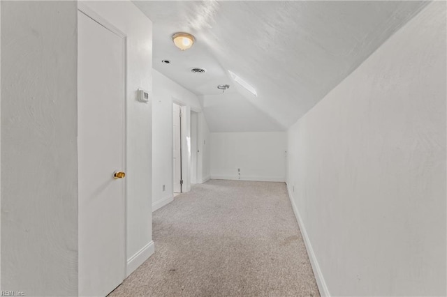 additional living space with light colored carpet and vaulted ceiling with skylight